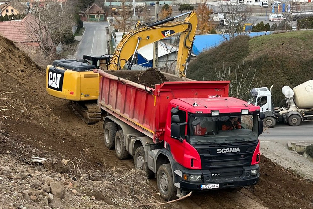 autobasculantă și excavator lucrând pe un șantier